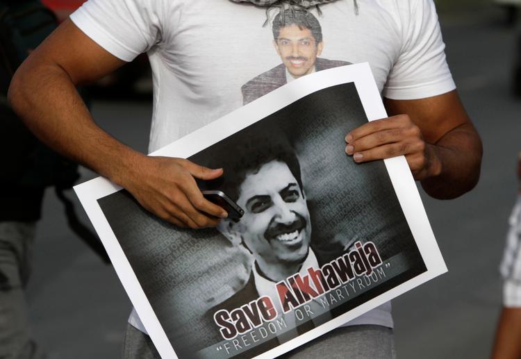 En demonstrant i Bahrain iklædt en t-shirt og med en plakat i hånden med billeder af Abdulhadi al-Khawaja i 2012. Foto: Hasan Jamali/Ritzau Scanpix