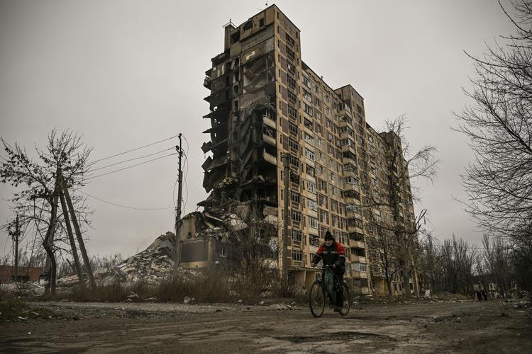 En mand cykler forbi en sønderbombet bygning i Avdiika i Donetsk. Nu er Den  Internationale Valutafond (IMF) er nået til enighed med Ukraine om en lånepakke til en værdi af cirka 15,6 milliarder dollar til at genopbygge landet. Foto: Aris Messinis/Ritzau Scanpix