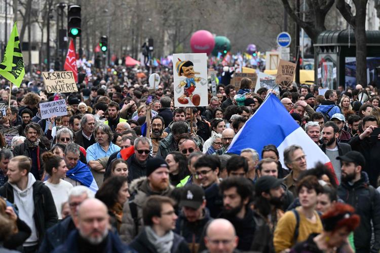 Store folkemængder demonstrerede i går mod den franske præsident, Macrons, pensionsreform. En af deltagerne i Paris  havde portrætteret Macron som Pinocchio på sit banner.  Foto: Emmanuel Dunand/Ritzau Scanpix