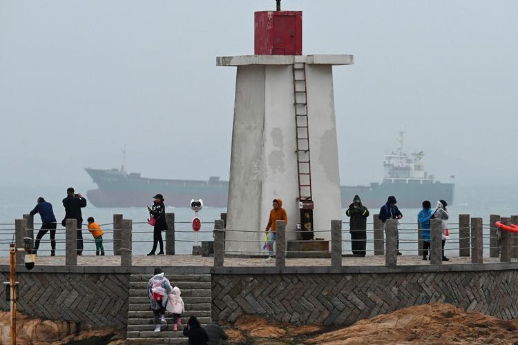 En last sejler i Taiwanstrædet bag turister på et fyrtårn på Pingtan-øen 6. april 2023. Foto: Greg Baker/Ritzau Scanpix