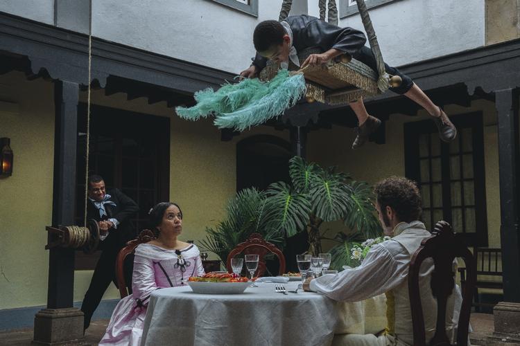 Den danske film fra 1987 ’Peter von Scholten’ tog titel og helt fra den hvide mand, der var guvernør på de dansk-vestindiske øer, dengang Danmark var slaveejende kolonimagt. Den biografaktuelle  ’Viften’ ændrer fortællevinkel og tager titel efter de slavegjorte børn, der blev brugt som menneskelige vifter over spisebordene.​ Framegrab SF STUDIOS