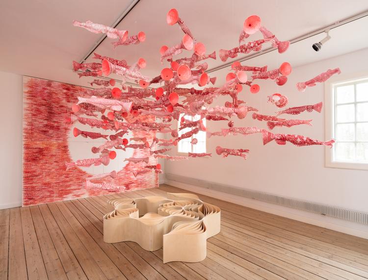 Flere hundrede flyvende papirfisk kæmper om opmærksomheden, mens Louise Campbell har placeret et lavt møbel på gulvet, der ligner et gennemskåret løg.  Foto: David Stjernholm