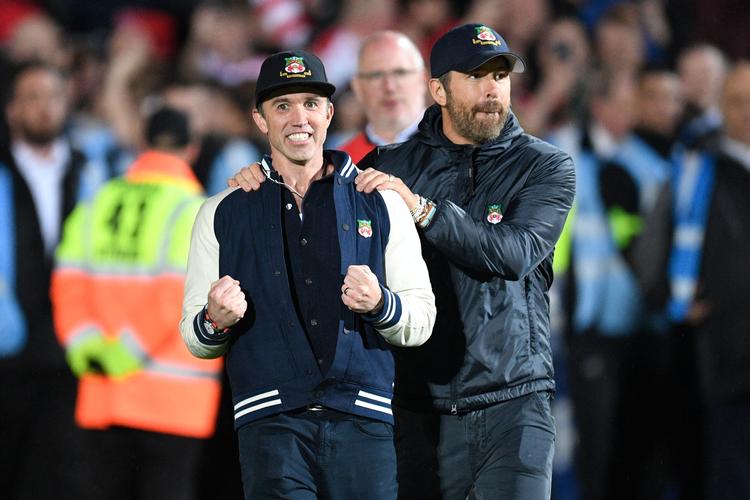 Klubejerne Ryan Reynolds (tv.) og Rob McElhenny måtte hele følelsesregistret igennem, inden de to Hollywood-stjerners klub Wrexham lørdag sikrede sig oprykning til Englands fjerdebedste fodboldrække med en 3-1-sejr over Boreham Wood, der kom foran allerede i første minut. Foto: Oli Scarff/Ritzau Scanpix