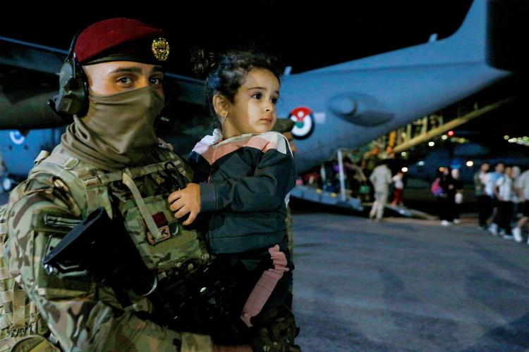 En soldat bærer et barn, der er blevet evakueret fra Sudan til Amman, Jordan.  Foto: Khalil Mazraawi/Ritzau Scanpix