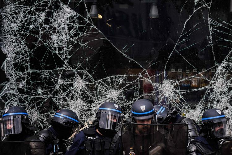Betjente foran et ødelagt butiksvindue i Lyon tidligere i dag.  Foto: Jeff Pachoud/Ritzau Scanpix