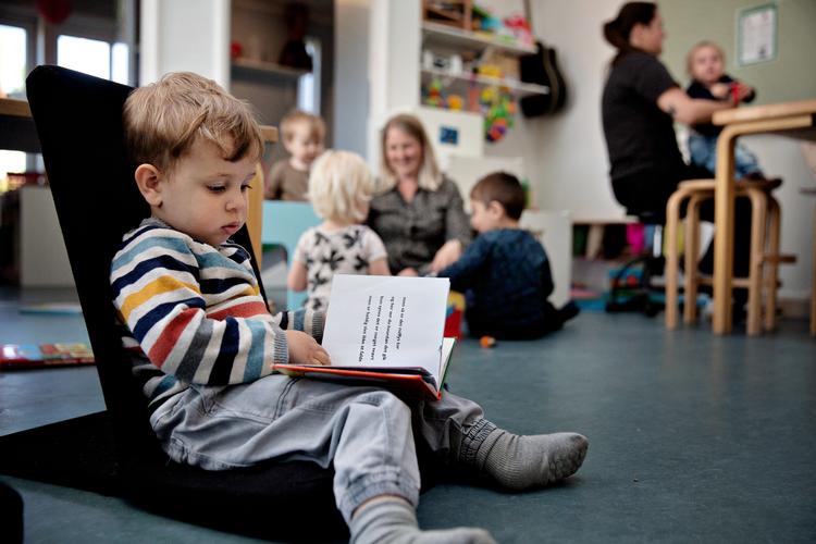 Noah har fundet sig en ny bog i bogreolen, efter at han har siddet hos pædagog Sasja Lehmann-Strøm og kigget i en bog om, hvilke rum der findes i et hus. Foto: Martin Lehmann