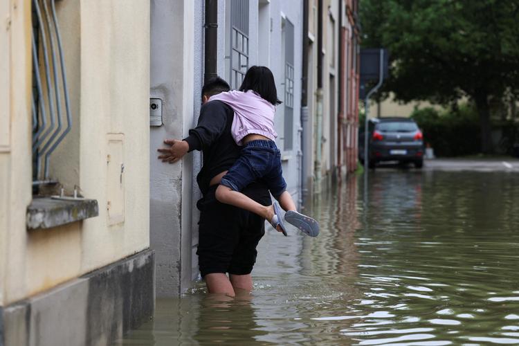 En mand redder et barn fra det stigende flodvand i Lugo i regionen Emilia Romagna i Italien.   Foto: Claudia Greco/Ritzau Scanpix