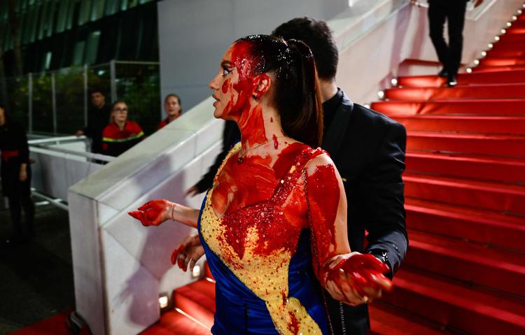 Før visningen af filmen 'Acide' smurte en kvindelig demonstrant sig  ind i falsk blod i en aktion i sympati med det ukrainske folk.  Foto: Christophe Simon/Ritzau Scanpix