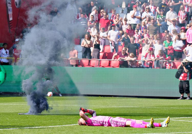 Triste AaB spillere smed sig i græsset, da nedrykningen var en realitet. Her ligger AaB's målmand Nico Mantl på banen, mens vrede fans affyrede røgbomber.  Foto: Henning Bagger/Ritzau Scanpix