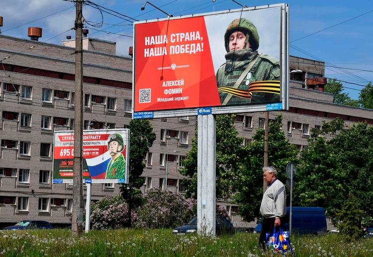  Russerne har vænnet sig til tanken om, at krigens afslutning ikke ligger lige om hjørnet. Her passerer en mand i Sankt Petersborg plakater, der hædrer soldaterne og forsøger at hverve flere.   Foto: Olga Maltseva/Ritzau Scanpix