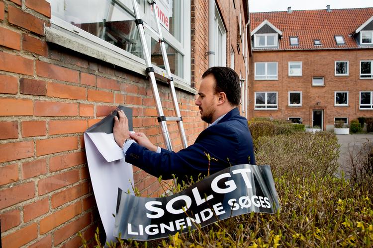 Ejendomsmægler Martin Porsmose sætter 'solgt'-skilt på en lejlighed i Brønshøj.   Foto: Finn Frandsen