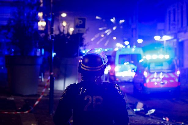     Fireworks explode as policemen stand by during protests in Roubaix, northern France on June 30, 2023, three days after a teenager was shot dead during a police traffic stop in the Paris suburb of Nanterre. Protests over the fatal police shooting of a teenager rocked France for a third straight night on June 29, with cars burned, buildings vandalised and hundreds arrested in cities across the country. The nighttime unrest followed a march earlier on Thursday in memory of the 17-year-old, named Nahel, whose death has revived longstanding grievances about policing and racial profiling in France's low-income and multiethnic suburbs. (Photo by Kenzo TRIBOUILLARD / AFP)   Foto: Kenzo Tribouillard/Ritzau Scanpix
