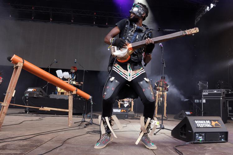 Fulu Miziki spiller hjemmelavede instrumenter af ting fra lossepladsen. En guitar bygget af en gammel bilradio og en panfløjte af grå plastikrør. Foto: Peter Hove Olesen