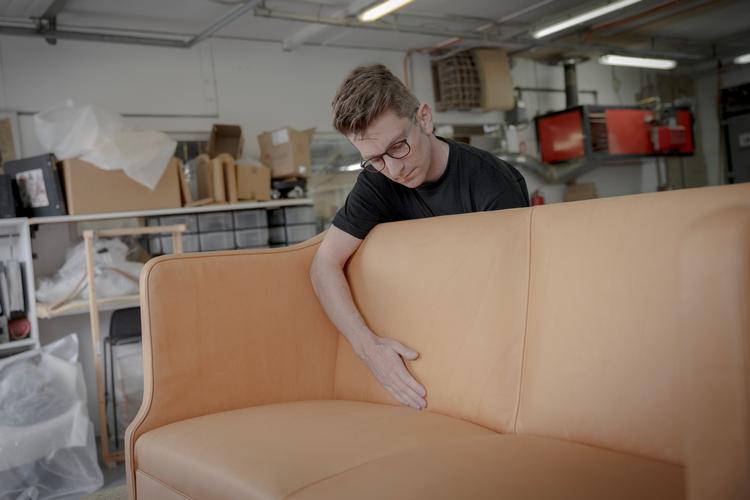 Bo Schønberg tjekker, om skindet sidder helt stramt på den gamle Kaare Klint-sofa, som har været pillet helt fra hinanden for at blive bygget op på ny.  Foto: Miriam Dalsgaard