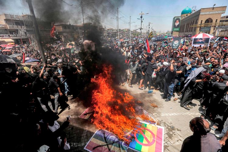 Demonstranter sætter ild til plakater af det svenske flag og prideflaget i Iraks hovedstad, Bagdad, 21. juli 2023. Foto: Murtaja Lateef/Ritzau Scanpix