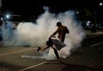 En borger fra favelaen Cidade de Deus (Guds By) i Rio de Janeiro sparker til en tåregasgranat, politiet har affyret, da der blev demonstreret efter et drab på en 13-årig dreng,  Foto: Tercio Teixeira/Ritzau Scanpix