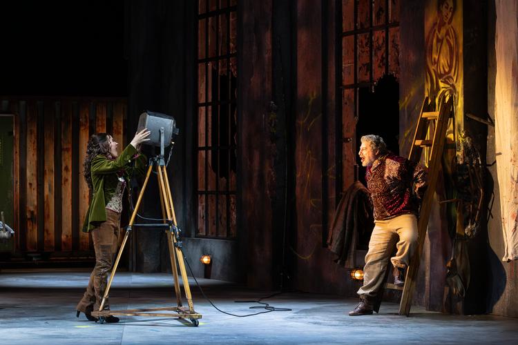 En projektør hjælper med at oplyse det meget mørke atelier, der udgør scenografien i 'Tosca'. Stefania Dovhan som Tosca lyser med den på instruktøren José Cura, der selv sang Cavaradossi ved premieren. Foto: Anders Bach