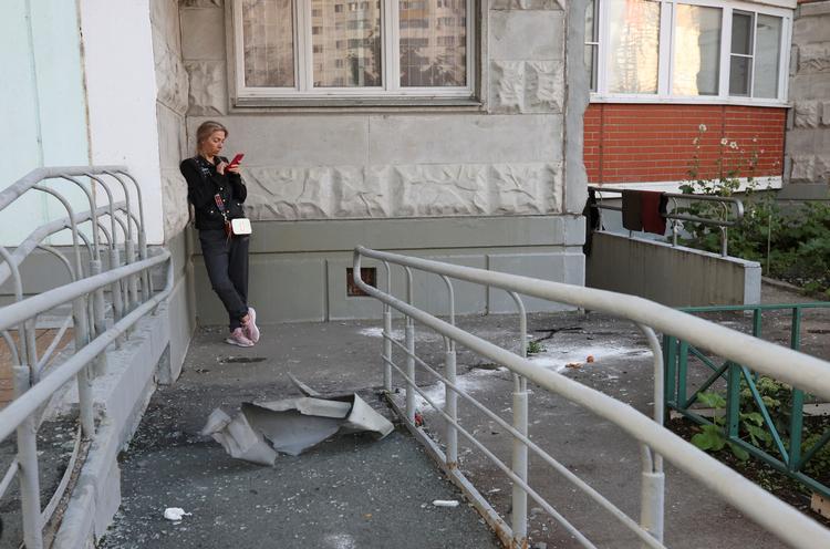 
En kvinde tjekker sin telefon ved siden af nedfalden materiale i byen Krasnogorsk, hvor en drone ifølge Rusland blev skudt ned natten til tirsdag. Foto: Stringer/Ritzau Scanpix