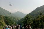 Lokale kigger på, mens en soldat hængende fra en militærhelikopter forsøger at nå ned til de otte personer, der sidder fast i en lift i landsbyen Pashto i det nordlige Pakistan. Foto: Prateek Kumar/Ritzau Scanpix