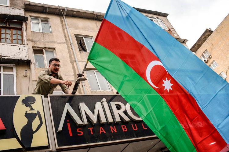 I Aserbajdsjans hovedstad, Baku, flager en borger for at støtte offensiven i Nagorno-Karabakh. Foto: Tofik Babayev/Ritzau Scanpix