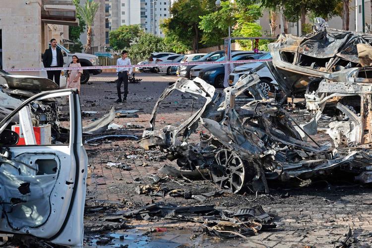 Indbyggere i den sydisraelske by Ashkelon betragter resterne af biler, der er blevet ramt i missilangrebet.  Foto: Ahmad Gharabli/Ritzau Scanpix
