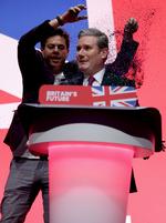 En aktivist kaster glitter på Labour-leder Keir Starmer, inden han skal begynde sin tale på Labours konference.   Foto: Phil Noble/Ritzau Scanpix