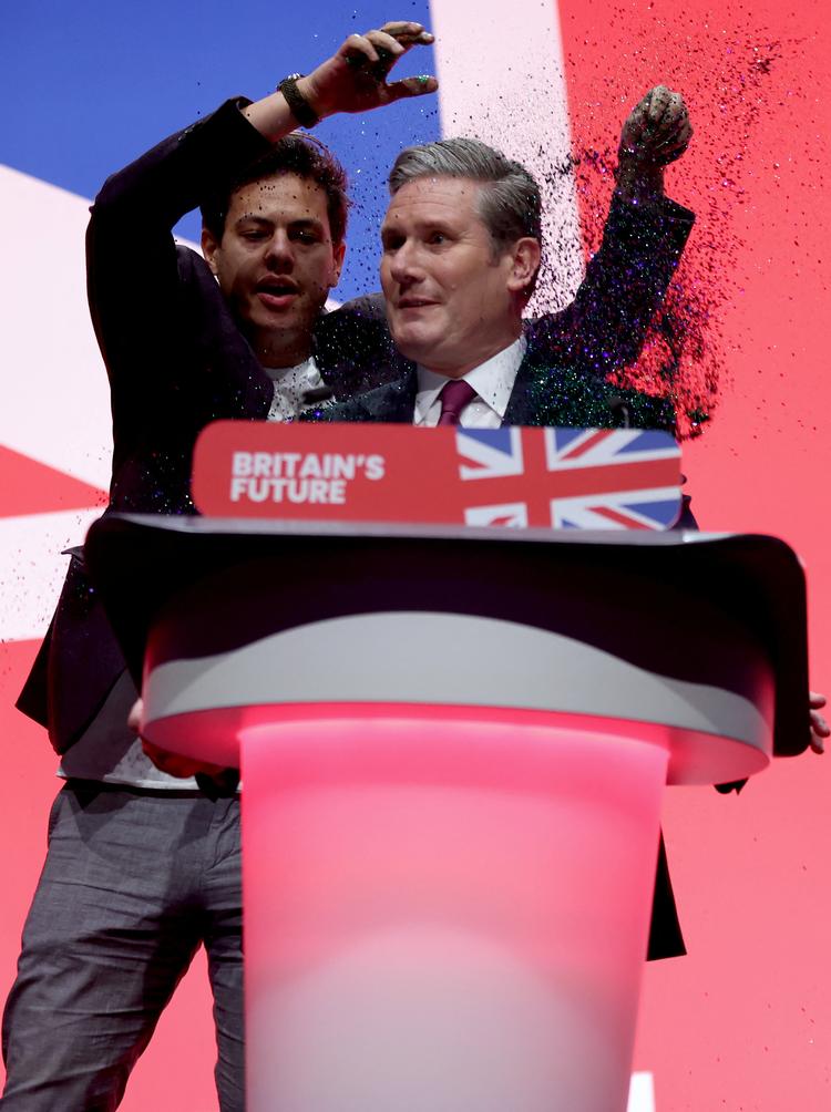 En aktivist kaster glitter på Labour-leder Keir Starmer, inden han skal begynde sin tale på Labours konference.   Foto: Phil Noble/Ritzau Scanpix