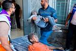 Nødhjælpsarbejdere hjælper sårede palæstinensiske børn ind på et hospital i Gaza.  Foto: Mohammed Abed/Ritzau Scanpix