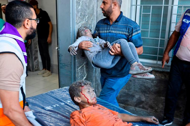 Nødhjælpsarbejdere hjælper sårede palæstinensiske børn ind på et hospital i Gaza.  Foto: Mohammed Abed/Ritzau Scanpix