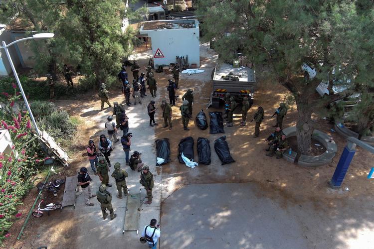 Israelske soldater og pressefolk i den hårdt ramte landsby Kfar Azza, hvor man stadig er i gang med at bjærge ofrene for angrebet lørdag morgen. Foto: Ilan Rosenberg/Ritzau Scanpix