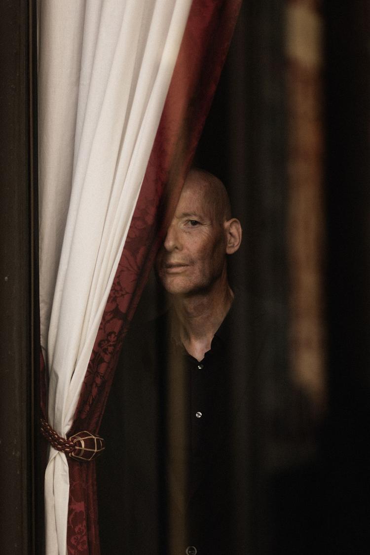 Festens midtpunkt kigger frem bag gardinet, som var det køreplaner for tog, der for længst er kørt ud på tilværelsens sidespor. Foto: Morten Larsen