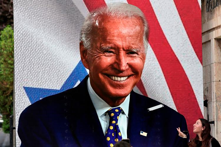 Kvinde poserer på en kæmpe plakat af den amerikanske præsident Joe Biden på en gade i Jerusalem 20. oktober 2023. Biden rejste til Israel den 18. oktober på et solidaritetsbesøg efter Hamas-angreb, der har ført til israelske repressalier på Gaza-striben. (Photo by Thomas COEX / AFP)   Foto: Thomas Coex/Ritzau Scanpix