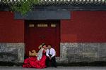 En kommende brud tørrer gommens ansigt, mens de venter på, at det bliver deres tur til at få taget det arrangerede foto i Den Forbudte By i Beijing. Foto: Andy Wong/Ritzau Scanpix