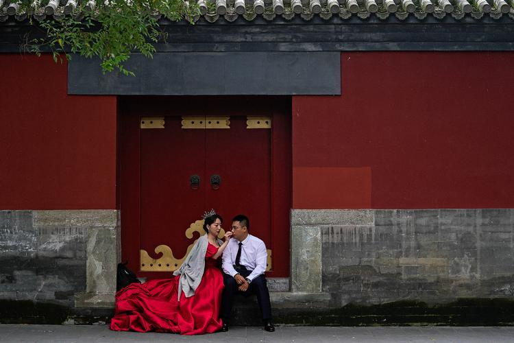 En kommende brud tørrer gommens ansigt, mens de venter på, at det bliver deres tur til at få taget det arrangerede foto i Den Forbudte By i Beijing. Foto: Andy Wong/Ritzau Scanpix