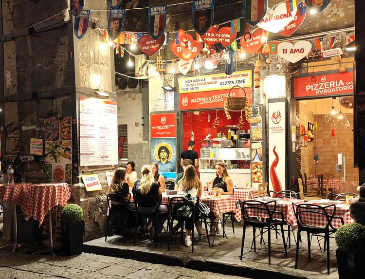 Man kan ikke gå et skridt i Napoli (og i regionens byer i det hele taget) uden at støde på et pizzeria, og bordene står tit tæt pakket på fortovene. Du spiser i de gamle gyder pyntet med skilte og flag, som fejrer byens fodboldholdhelte. Foto: Maria Cristina Castellucci