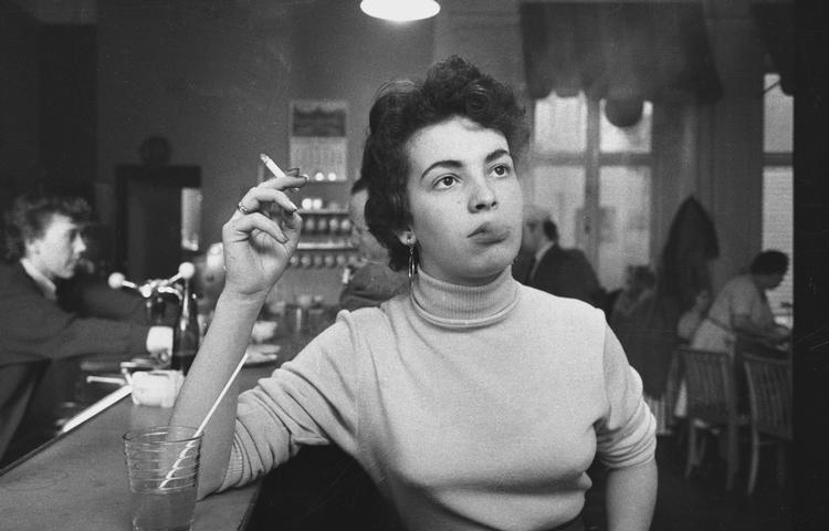 Ung rygende kvinde, fotograferet af Erik Petersen, muligvis i 1958-59 på Willis Place i Vester Voldgade, byens første milkshakebar efter amerikansk forbillede.  Foto: Erik Petersen