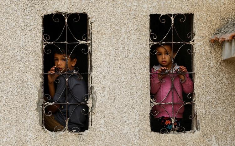 Palæstinensiske børn kigger ud vinduer i et område ramt af israelske bombardementer.  Foto: Ibraheem Abu Mustafa/Ritzau Scanpix