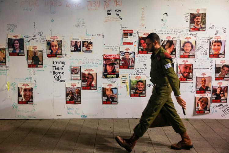 En israelsk soldat passerer en væg, som bærer budskabet 'Bring them home'. En kommentar til den israelske regering om at få alle gidsler hjem, som holdes fanget i Gaza.  Foto: Ahmad Gharabli/Ritzau Scanpix