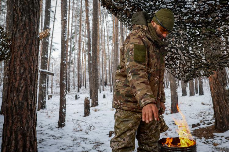 En ukrainsk soldat varmer sine forfrosne hænder over en hjemmelavet brænder i den nyfaldne sne i Donetskregionen for præcis et år siden. Foto: Alina Smutko/Ritzau Scanpix
