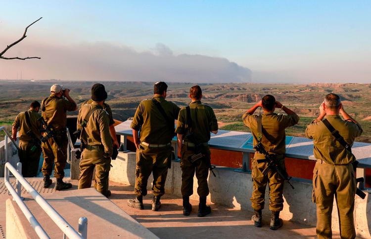 Israelske soldater holder øje med røgen over det palæstinensiske område efter et nyt bombardement i Gaza.  Foto: Menahem Kahana/Ritzau Scanpix