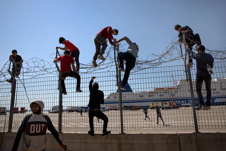 Migranter kravler over et hegn i Grækenland, så de kan komme om bord i lastbiler, der skal videre op i Europa.. Arkivfoto. Foto: Jacob Ehrbahn