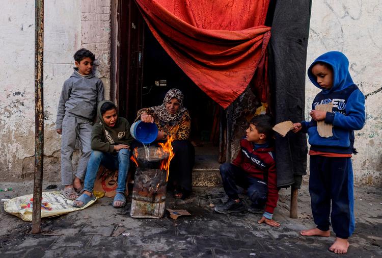 På dette billede taget 22. december laver en palæstinensisk kvinde i Gaza mad til sin familie uden for et hus i det sydlige Gaza. Ifølge ny rapport springer mange voksne i Gaza et eller flere måltider over for at give maden til deres børn. Foto: Mohammed Abed/Ritzau Scanpix