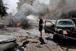 En mand i den israelske by Ashkelon forsøger at slukke branden i en bil, efter at den er blevet ramt af raketter affyret fra Gaza under Hamas' store angerb 7. oktober.  Foto: Ammar Awad/Ritzau Scanpix
