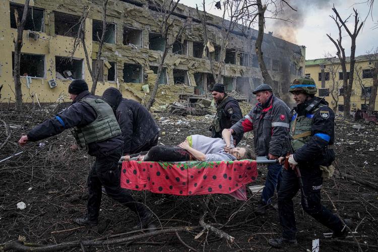 Ukrainske redningsfolk forsøger at hjælpe en gravid kvinde i sikkerhed under russernes bombardement af Mariupol i krigens første måneder - kvinden og hendes barn døde senere.  Foto: Evgeniy Maloletka/Ritzau Scanpix