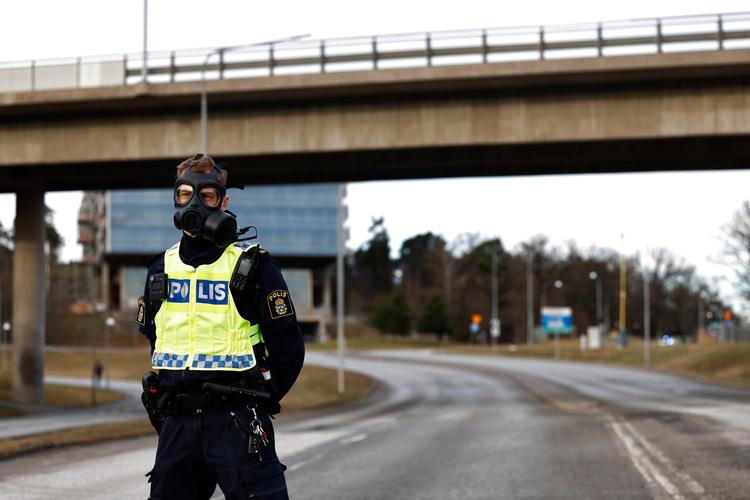 En gasmaskeklædt betjent holder vagt ved Säpos hovedkvarter i Solna nord for Stockholm. Foto: 1081 Fredrik Persson/Ritzau Scanpix