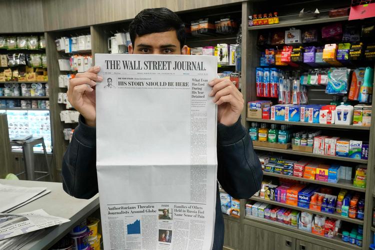 En avissælger i New York holder fredagens udgave af The Wall Street Journal op foran sig. Forsiden af avisen domineres af et hvidt felt som en markering af årsdagen for fængslingen af avisens journalist Evan Gershkovich, der blev anholdt for præcis et år siden og sidder i et russisk fængsel anklaget for at indsamle oplysninger for USA. Foto: Timothy A. Clary/Ritzau Scanpix