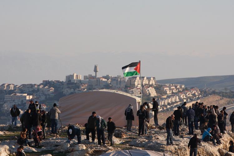 Palæstinensere, støttet af internationale aktivister, demonstrerer mod israelske bosættere, som har opsat et telt i området mellem Jerusalem og bosættelsen Maaleh Adumim. Israels højreregering vil gerne bebygge området for at splitte den besatte Vestbred ad og hindre, at der kan blive en sammenhængende palæstinensisk stat. Foto: Majdi Mohammed/Ritzau Scanpix