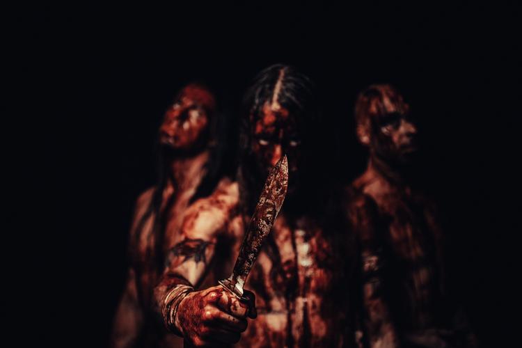 Martin Leth Andersen (midtfor med kniv) i front for Strychnos. Til venstre ses trommeslager Nis Rode Larsen og til højre guitarist Andreas Lynge. Foto: Martin Goltermann