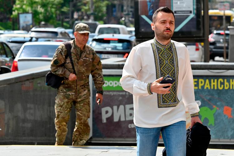 Kyiv i dag. En mand bærer en traditionel dragt på den nationale dag for netop traditiionelle dragter. Bagved ham ses en ukrainsk soldat. Foto: Sergei Supinsky/Ritzau Scanpix