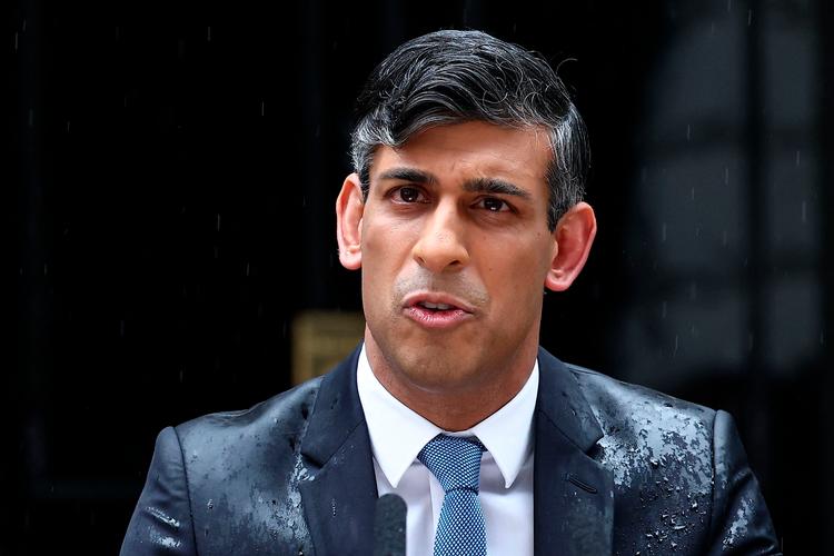 Den velklædte stil kunne ikke redde premierminister Rishi Sunak, da han i silende regn stod foran Downing Street 10, som en gennemblødt dørsælger og udskrev valg.  Foto: Henry Nicholls/Ritzau Scanpix